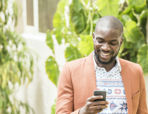 African man using cell phone, smiling