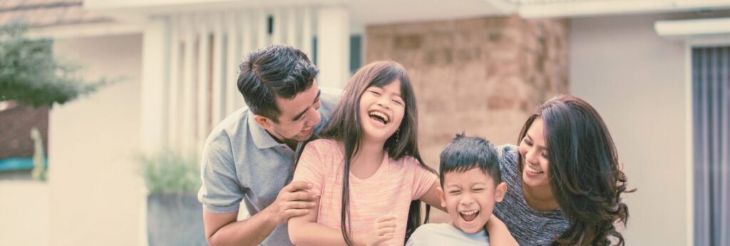 A happy family in Australia in front their new home. First Home Scheme Australia

 
