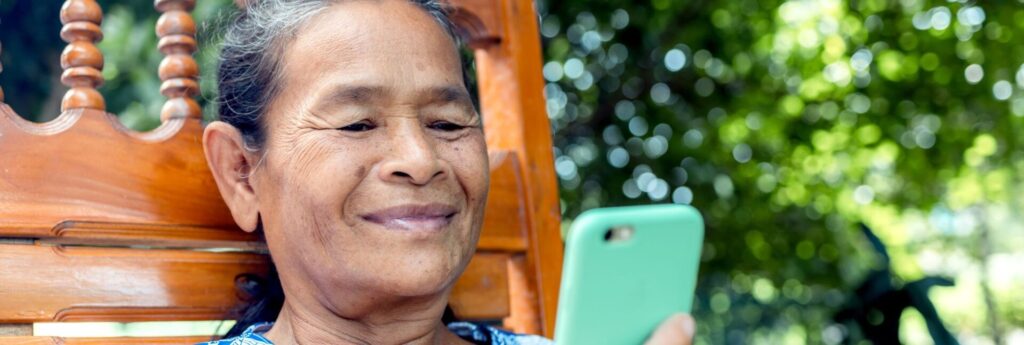 Mother smiling while looking at her phone. long distance Mother's Day message from her child overseas